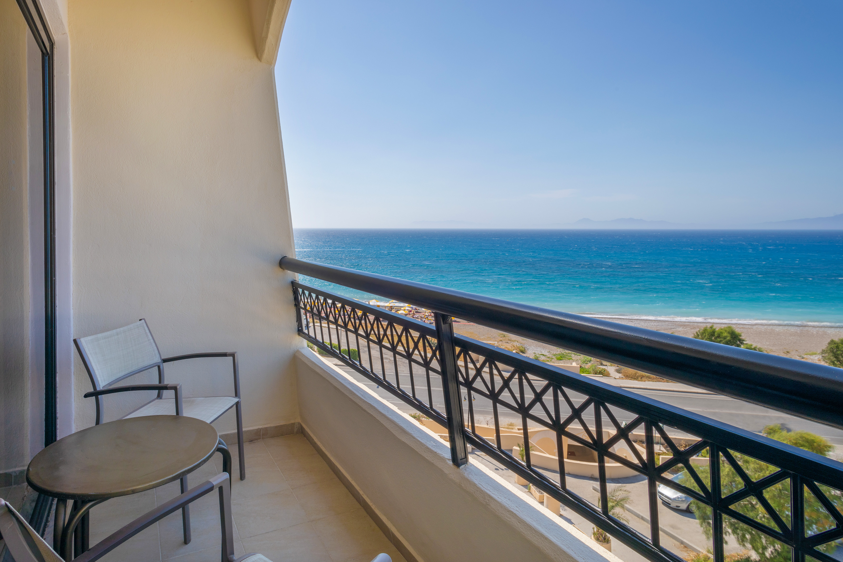 Balcony overlooking blue ocean, beach, and coastal road.