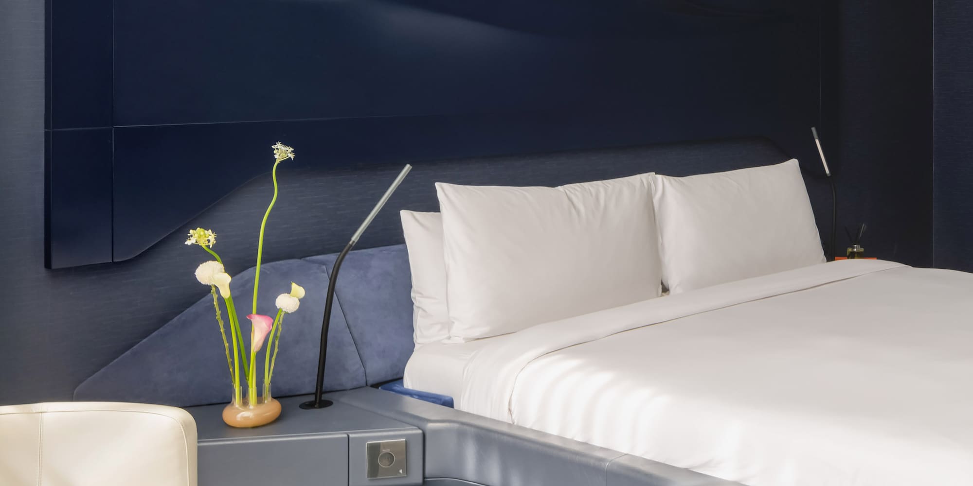 a bed with a white sheet and a white chair.