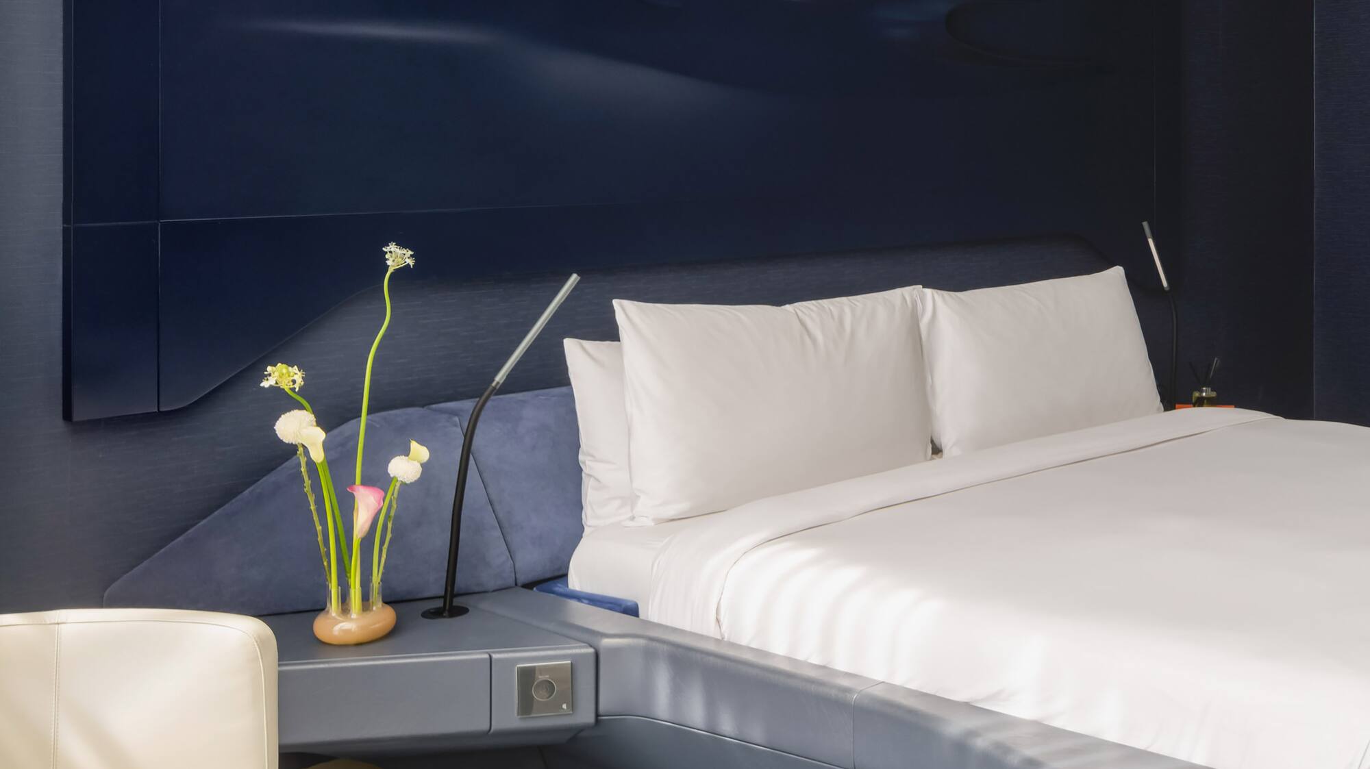 a bed with a white sheet and a white chair.