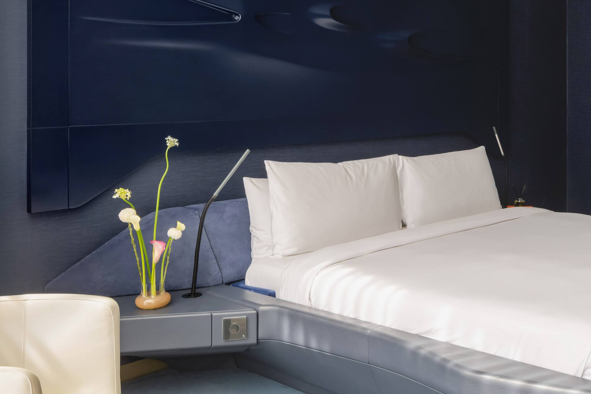 a bed with a white sheet and a white chair.