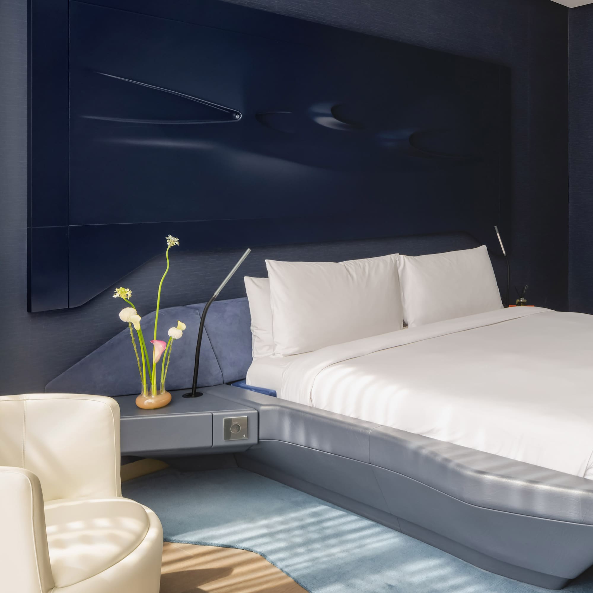 a bed with a white sheet and a white chair.