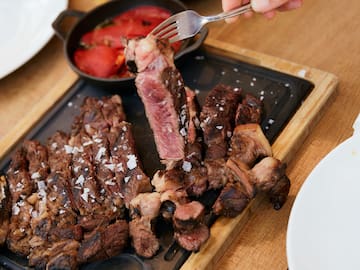 a person holding a fork over a plate of meat