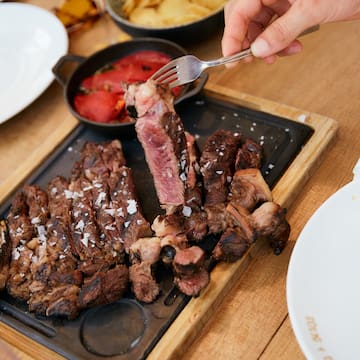 une personne tenant une fourchette sur une assiette de viande