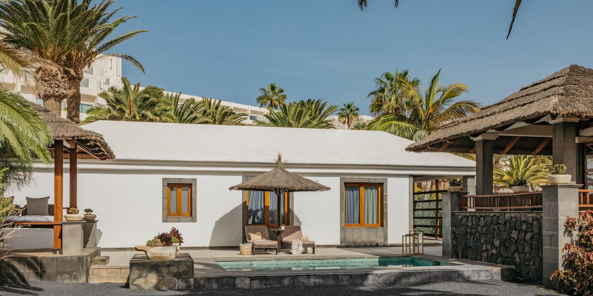 a white building with a pool and umbrellas