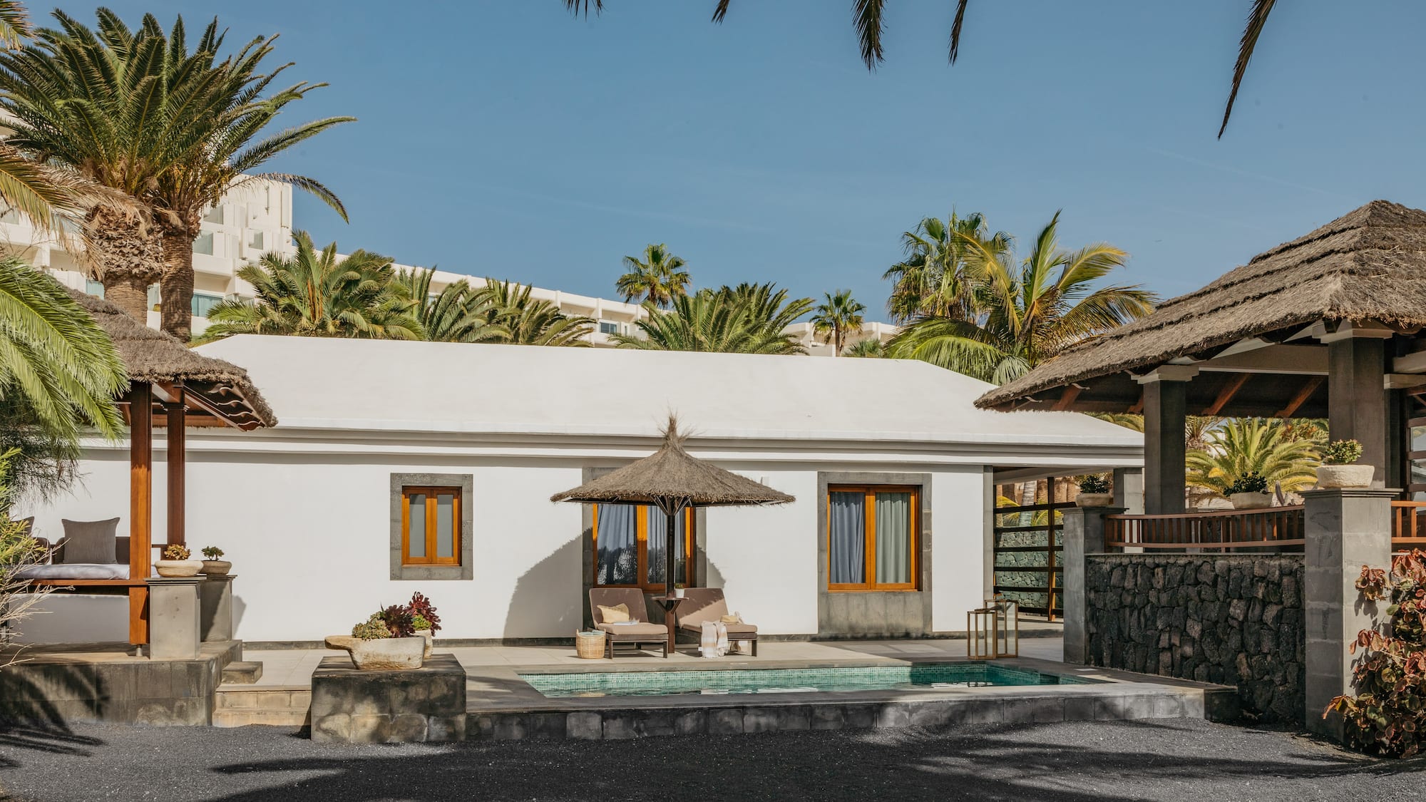 a white building with a pool and umbrellas