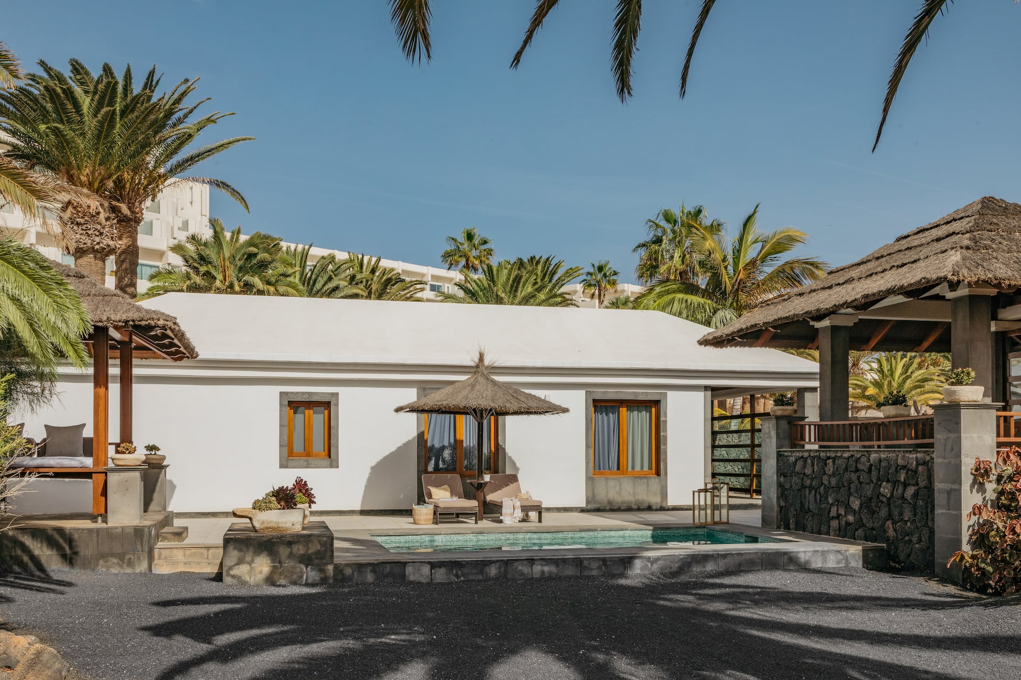 a white building with a pool and umbrellas