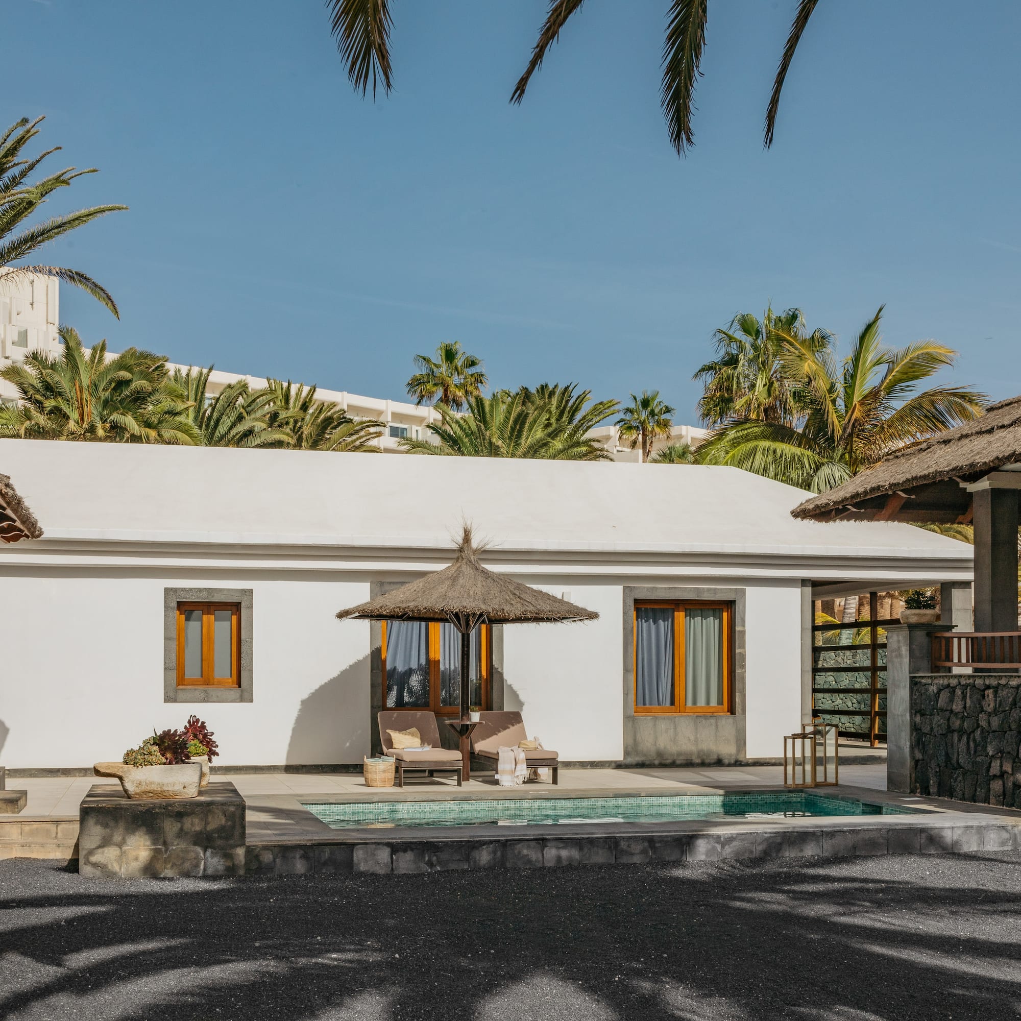 a white building with a pool and umbrellas