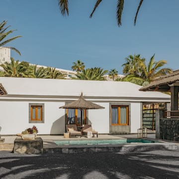 a white building with a pool and umbrellas