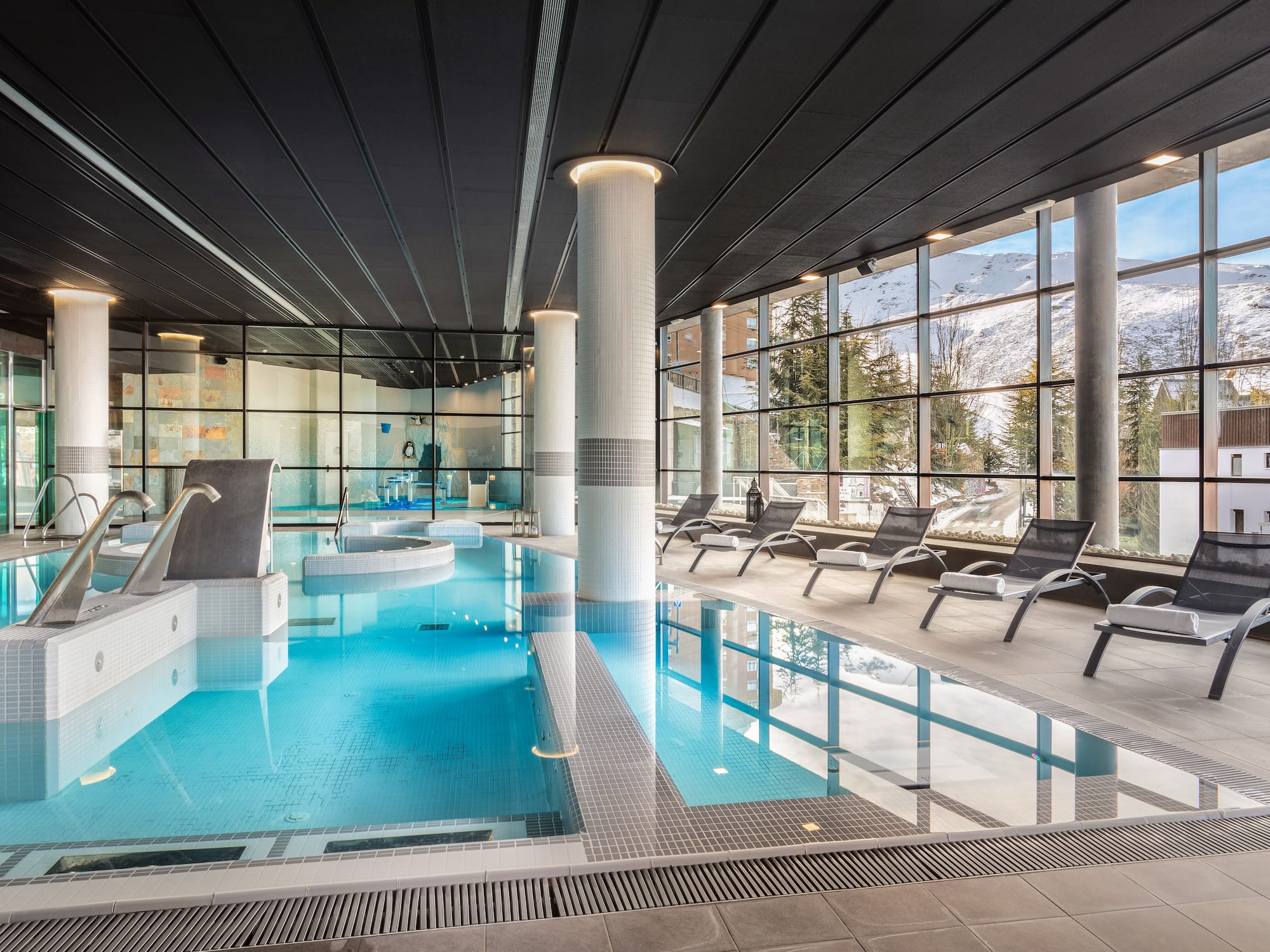a indoor pool with chairs and a large window