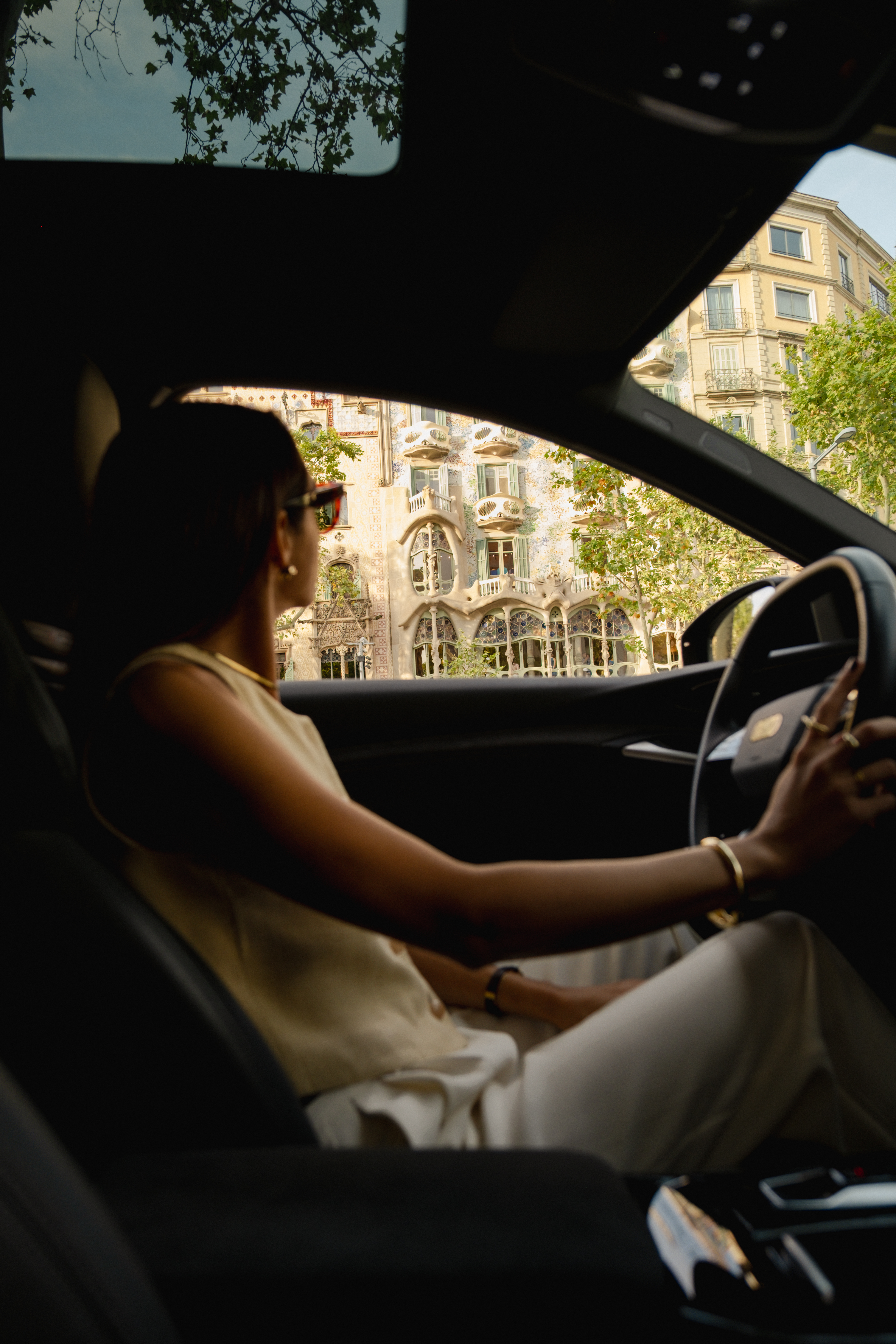Woman driving past Casa Batlló, iconic Barcelona architecture.