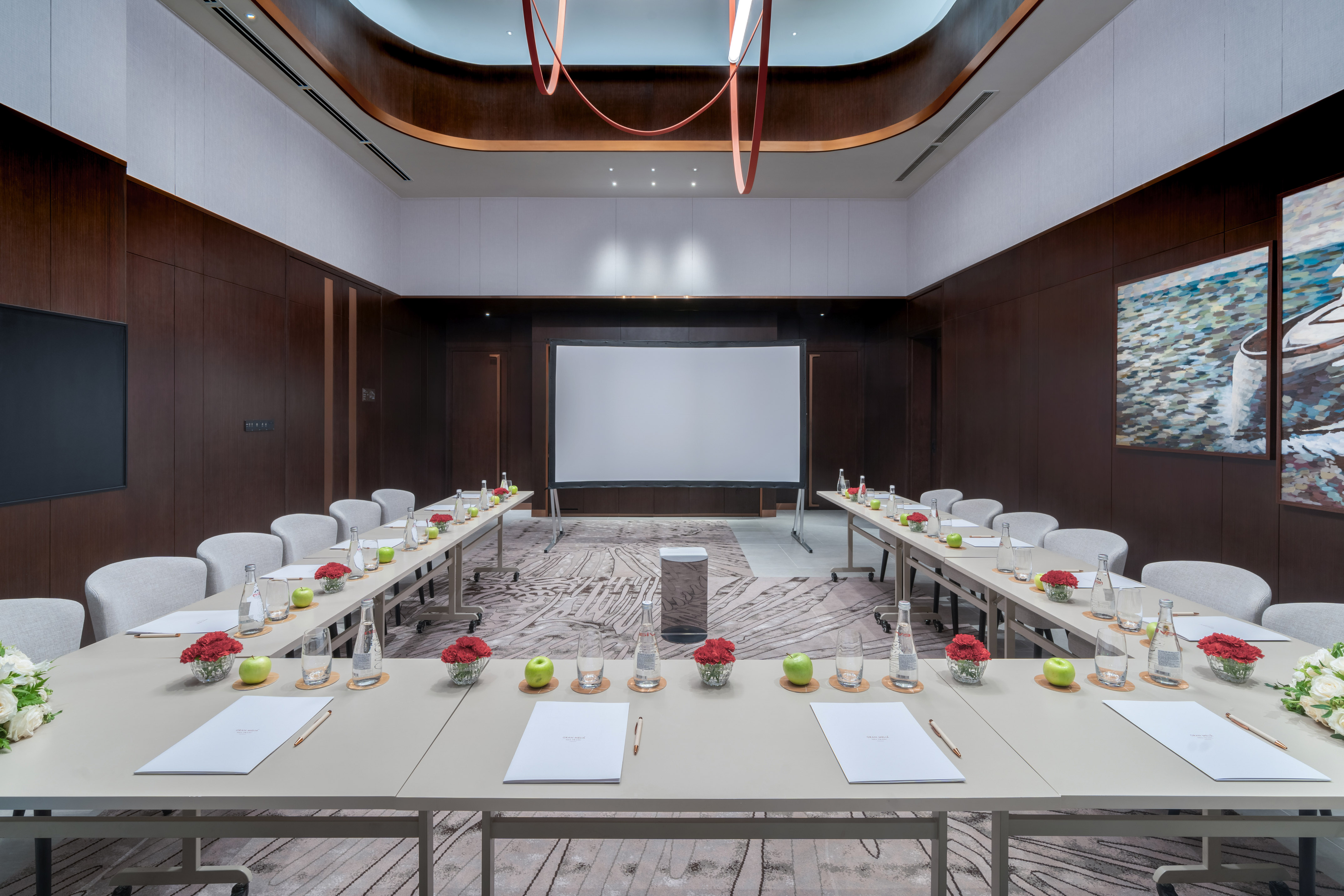 U-shaped conference room with projection screen, elegant tables for corporate events.