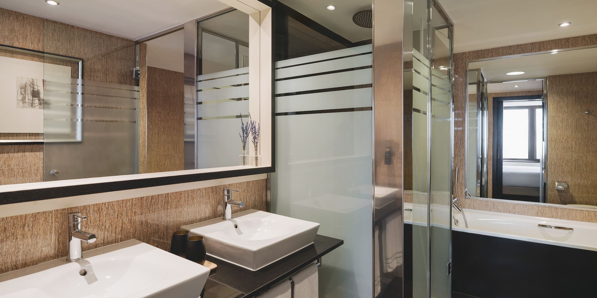 Elegante baño de hotel con doble lavabo, ducha de cristal y bañera.