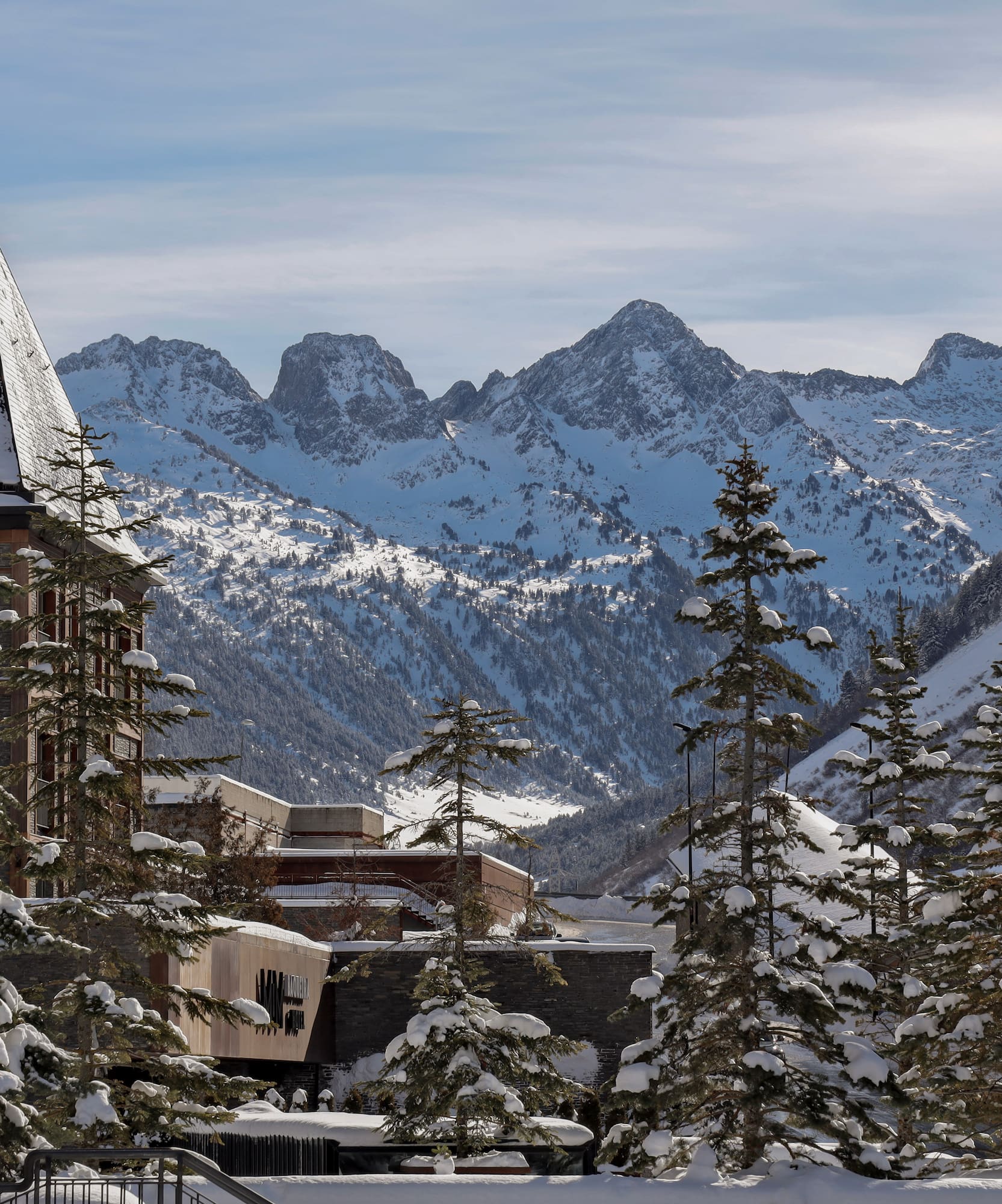 a snowy mountain range with buildings and trees