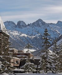 a snowy mountain range with buildings and trees