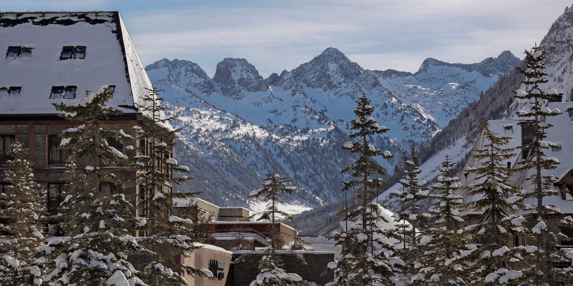 a snowy mountain range with buildings and trees