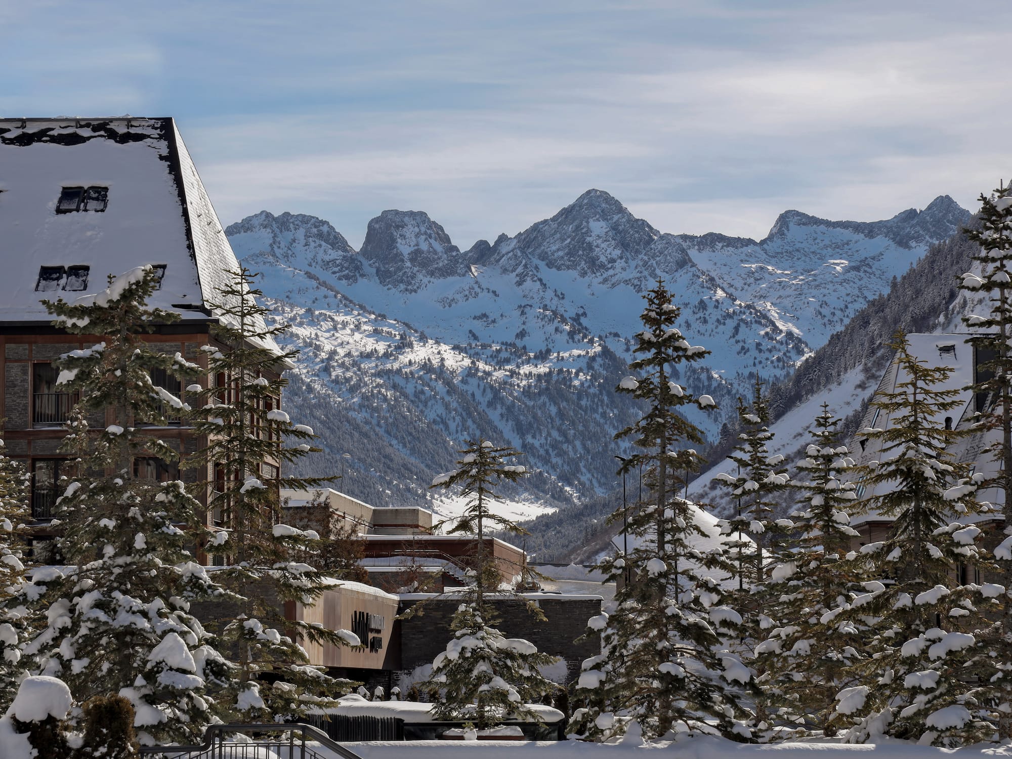 a snowy mountain range with buildings and trees