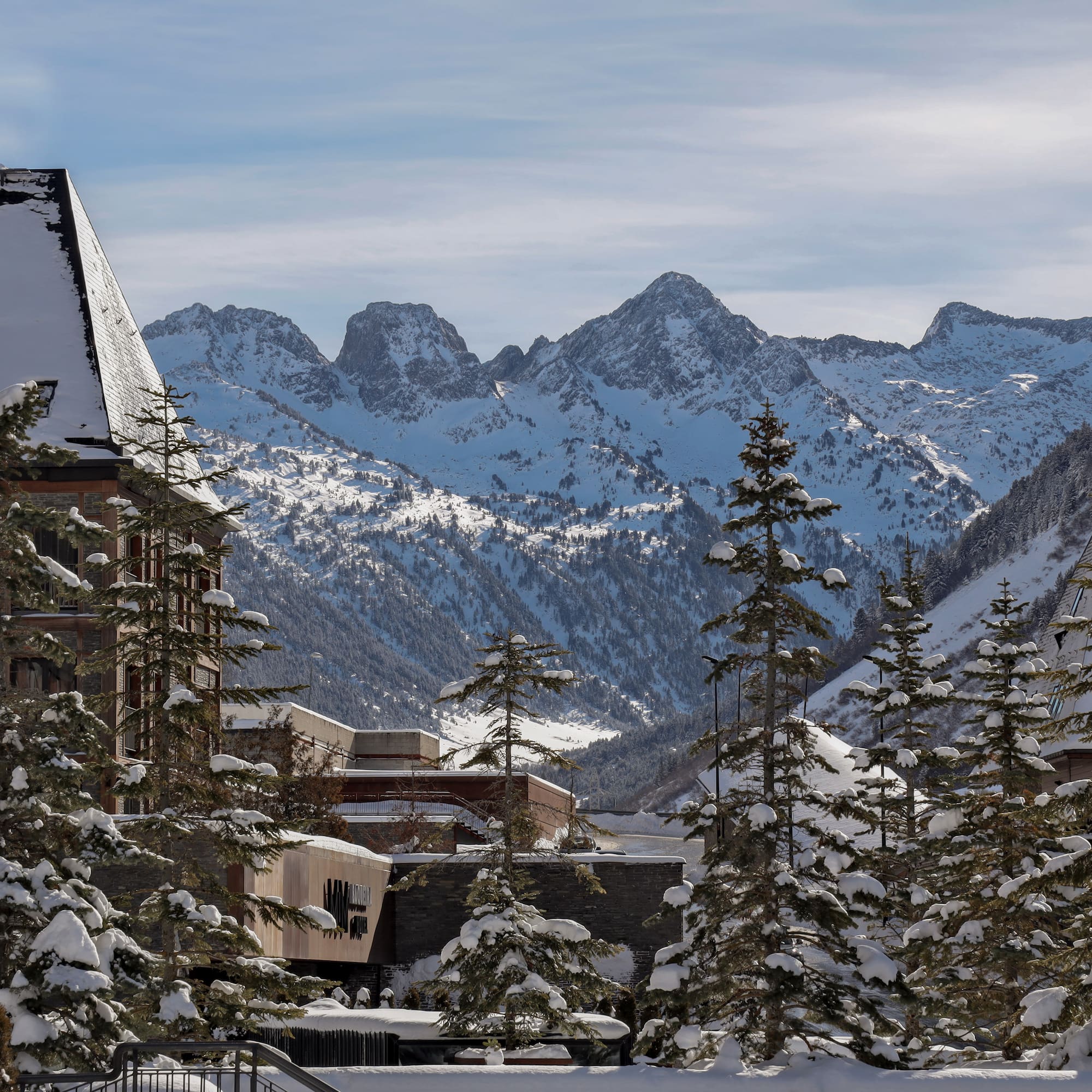 a snowy mountain range with buildings and trees