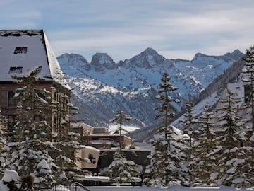 a snowy mountain range with buildings and trees