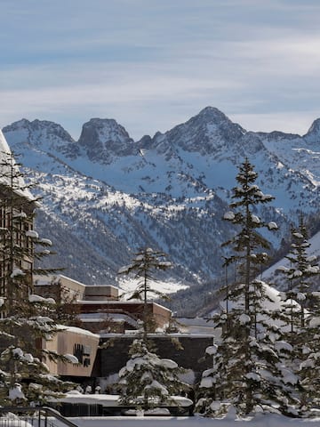 a snowy mountain range with buildings and trees