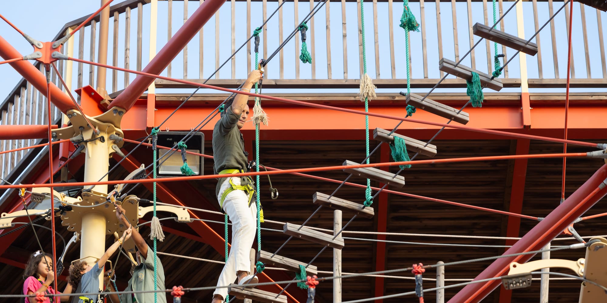 Adult climbing rope ladder on a high ropes course at an adventure park.