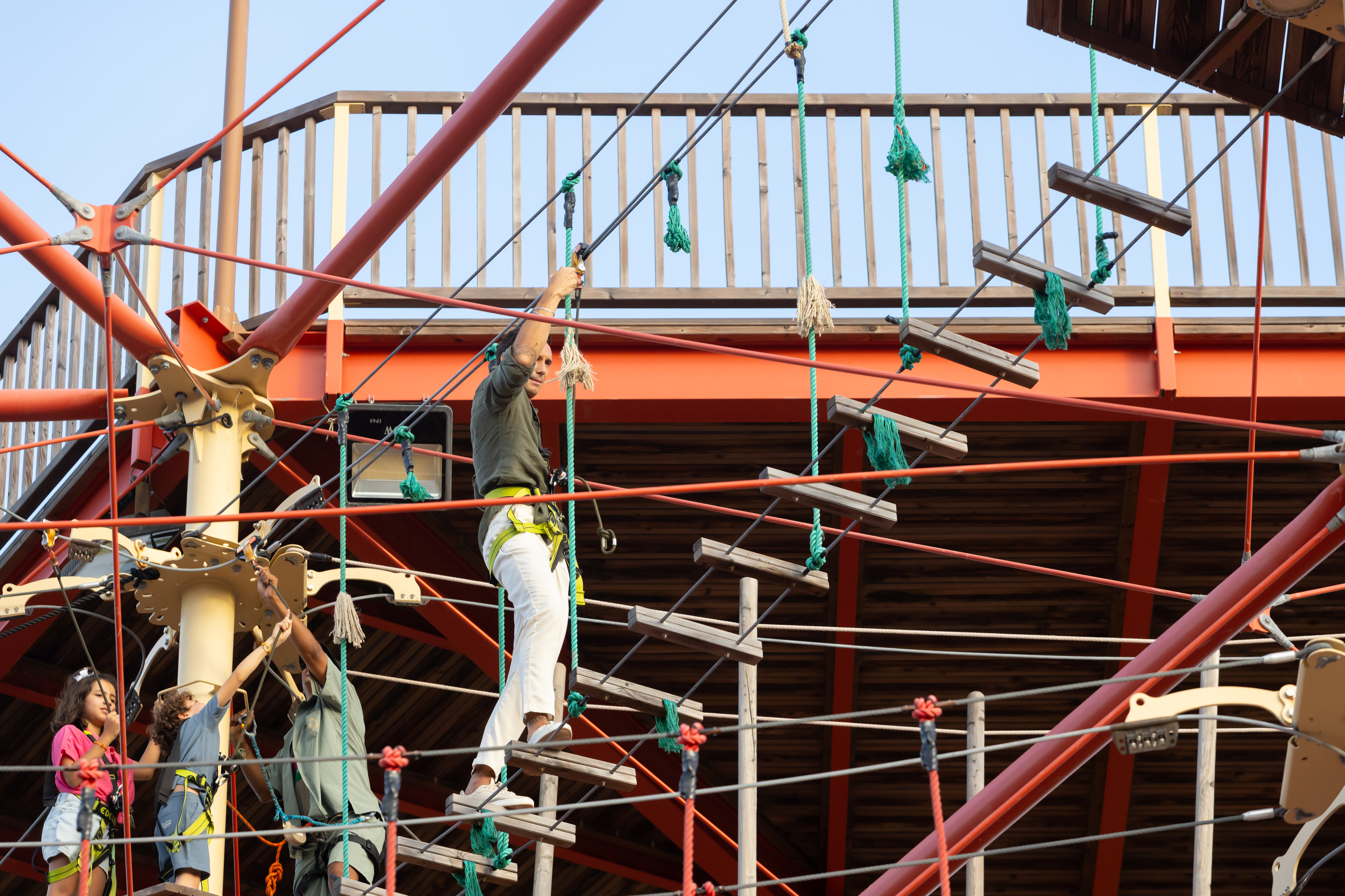 Adult climbing rope ladder on a high ropes course at an adventure park.