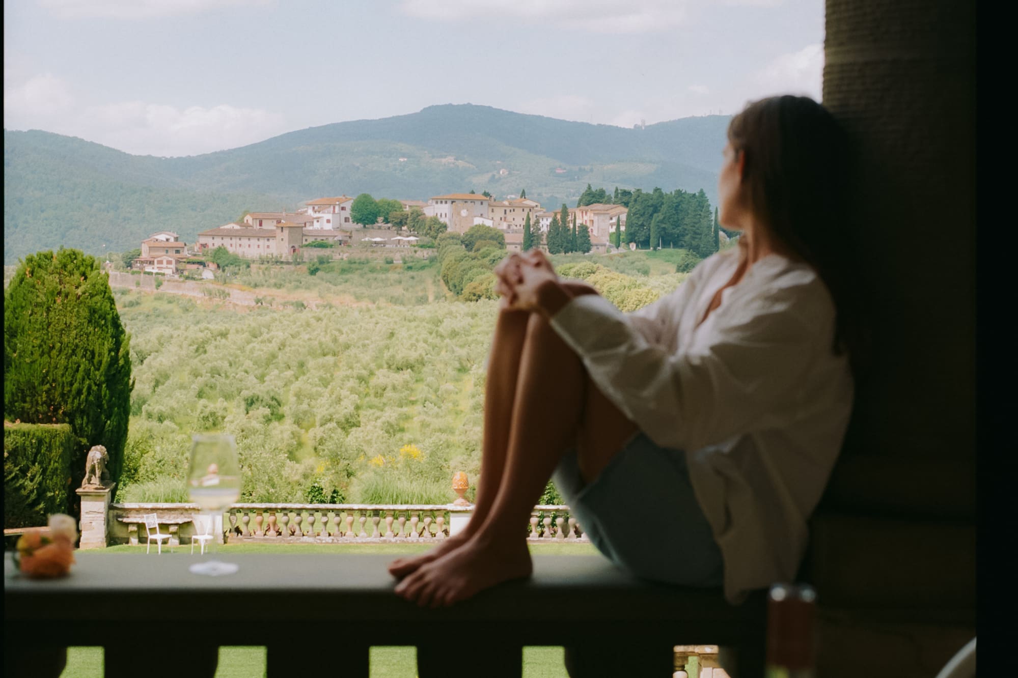 a woman sitting on a balcony looking out a window