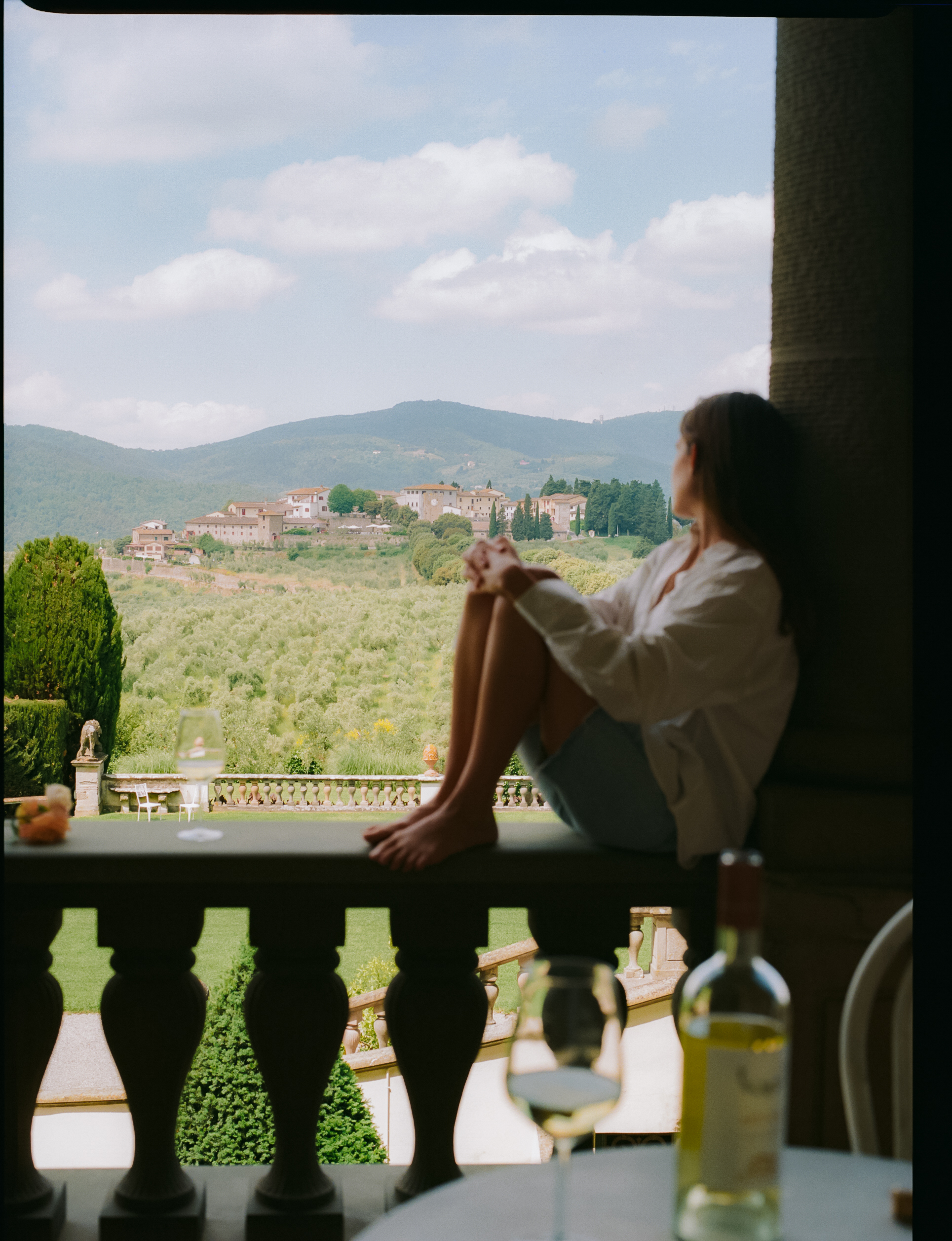 a woman sitting on a balcony looking out a window