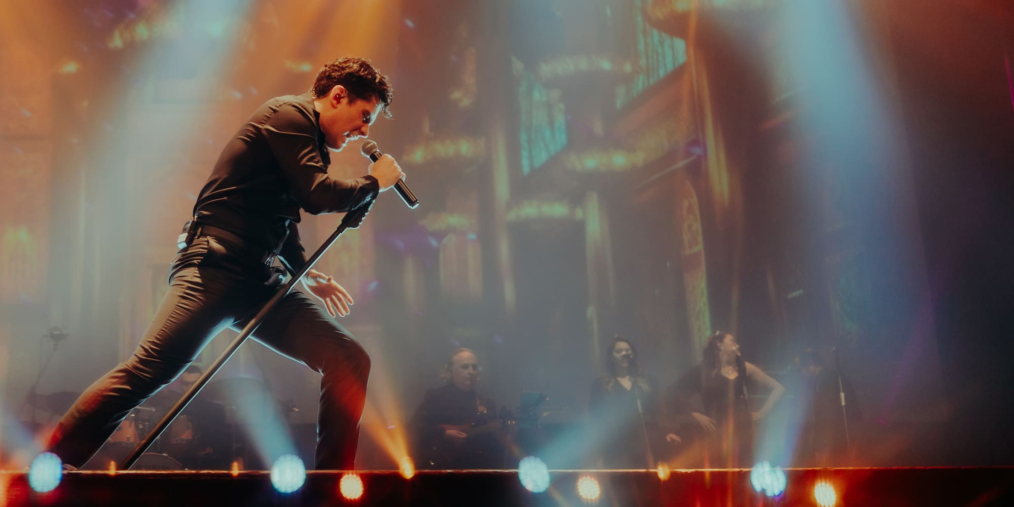 a man singing into a microphone on a stage