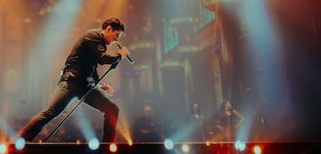 a man singing into a microphone on a stage