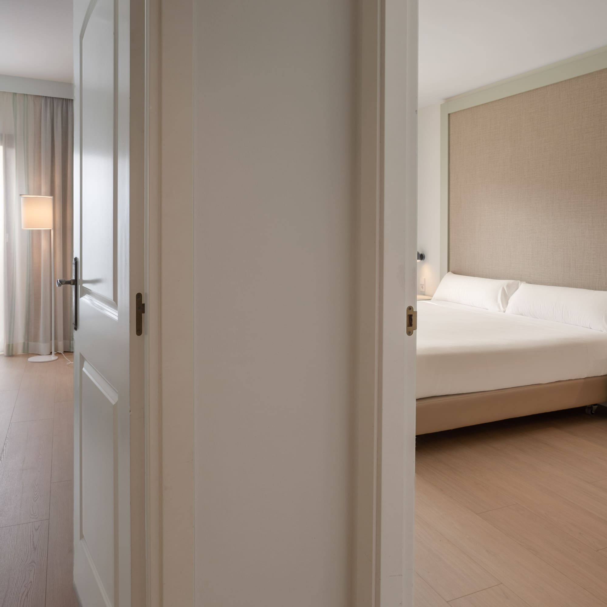 Two hotel rooms with twin and double beds, modern interior, light wood floor.