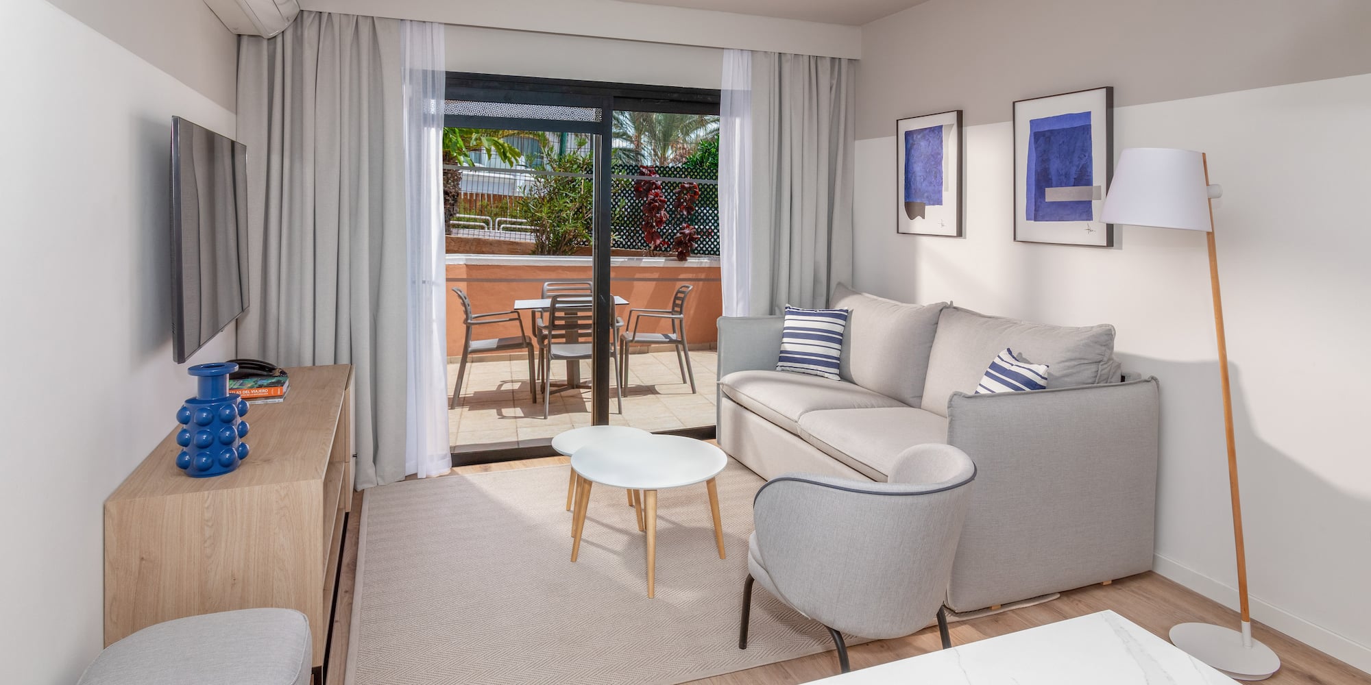 Modern apartment living room with sofa, balcony, and light wood floor.