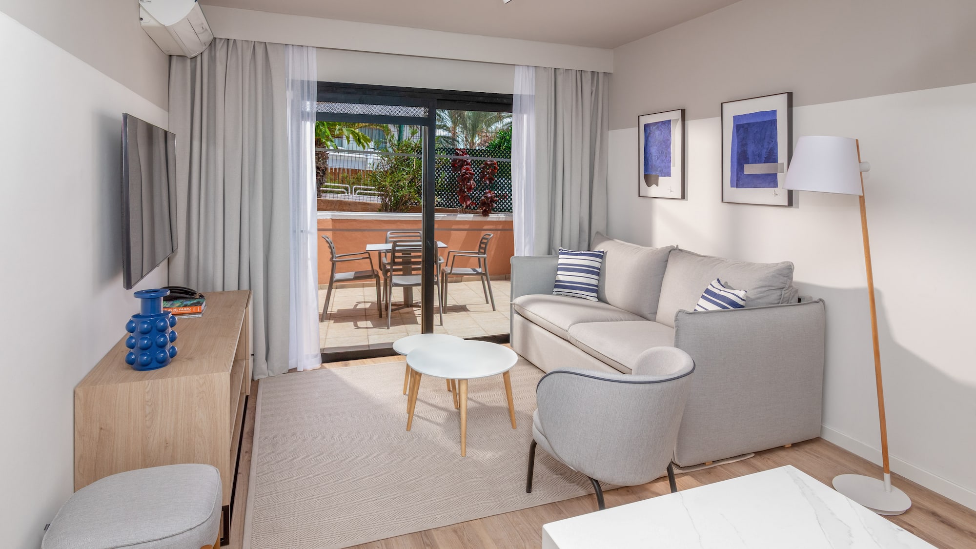 Modern apartment living room with sofa, balcony, and light wood floor.