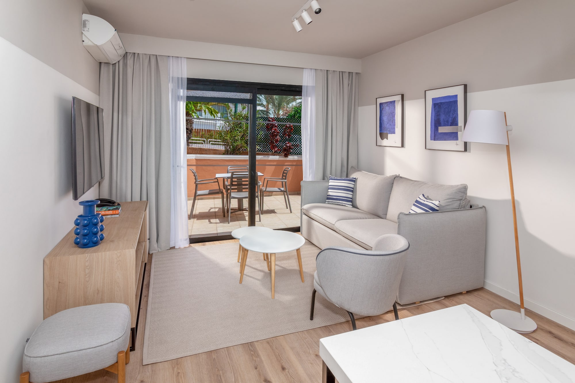 Modern apartment living room with sofa, balcony, and light wood floor.