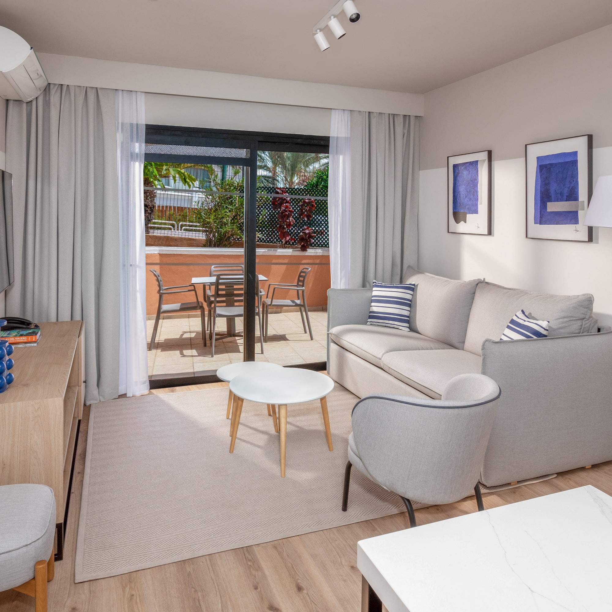 Modern apartment living room with sofa, balcony, and light wood floor.