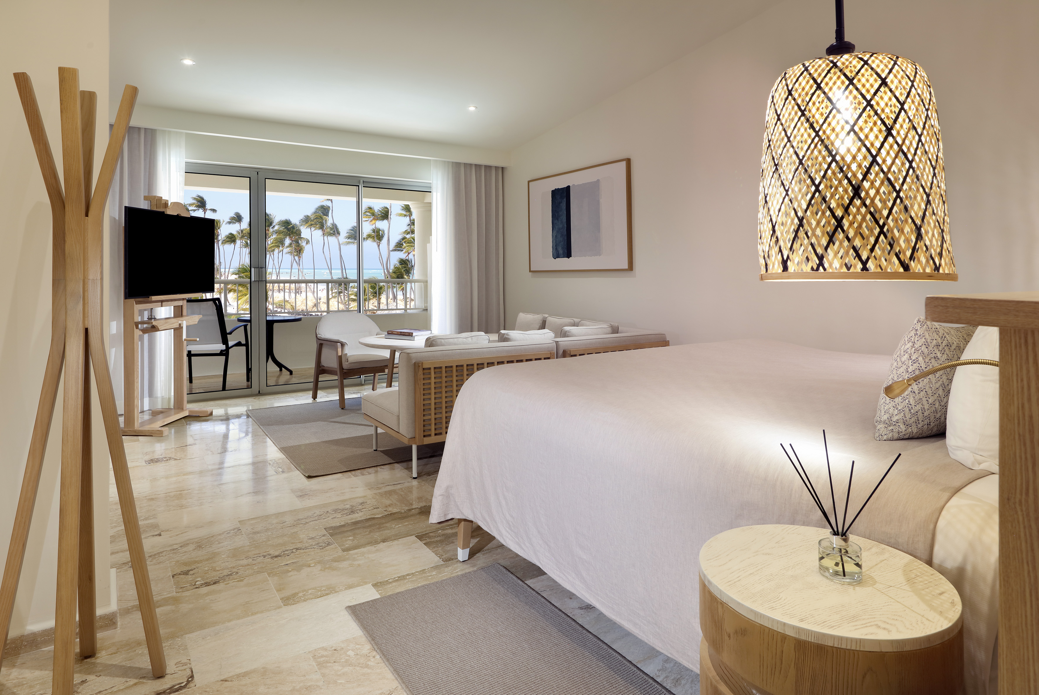 Tropical hotel suite with ocean view balcony, king bed, and modern living area.
