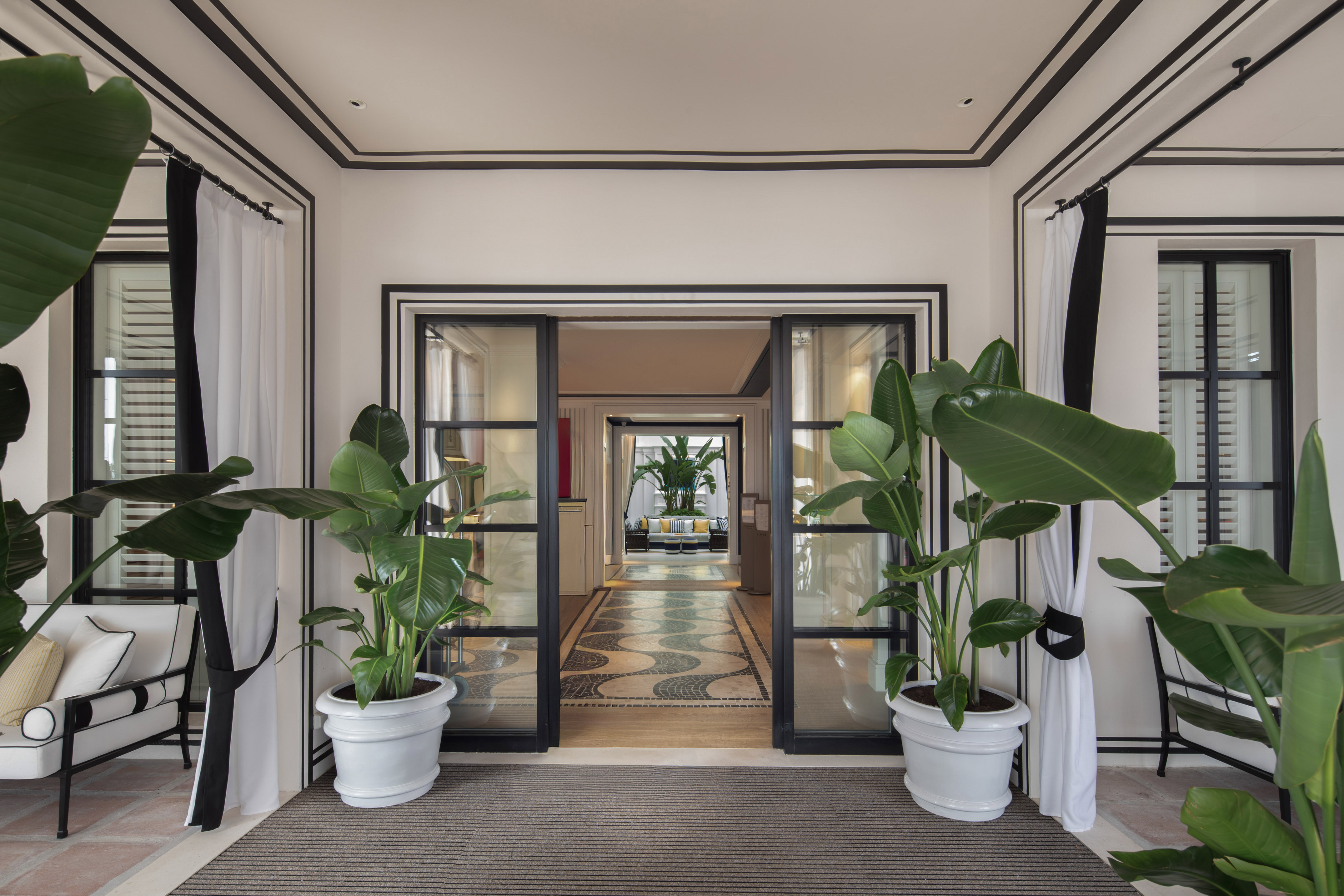 Luxury hotel foyer, tropical plants, black and white decor, mosaic floor.