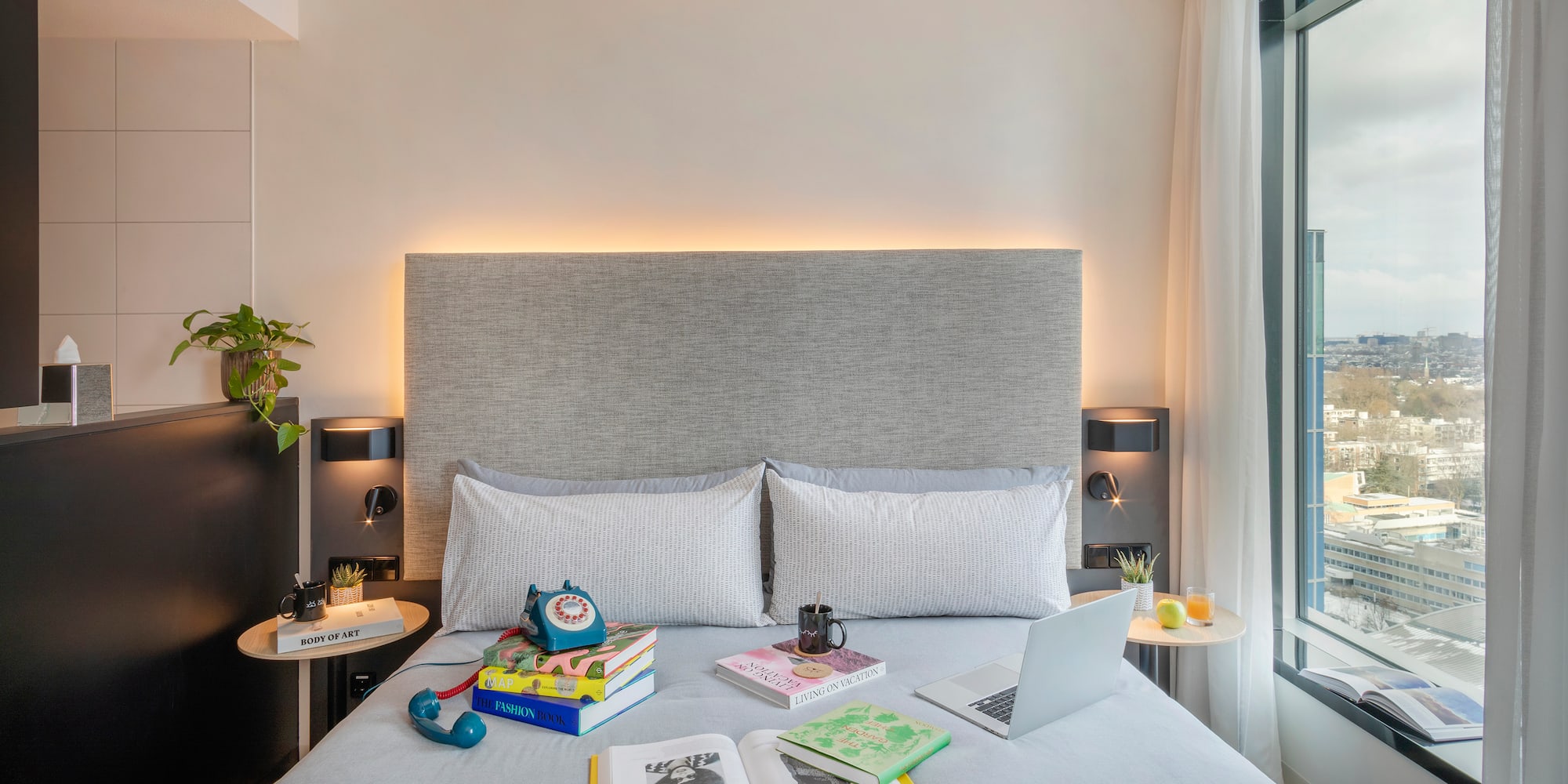 a bed with a laptop and books on it