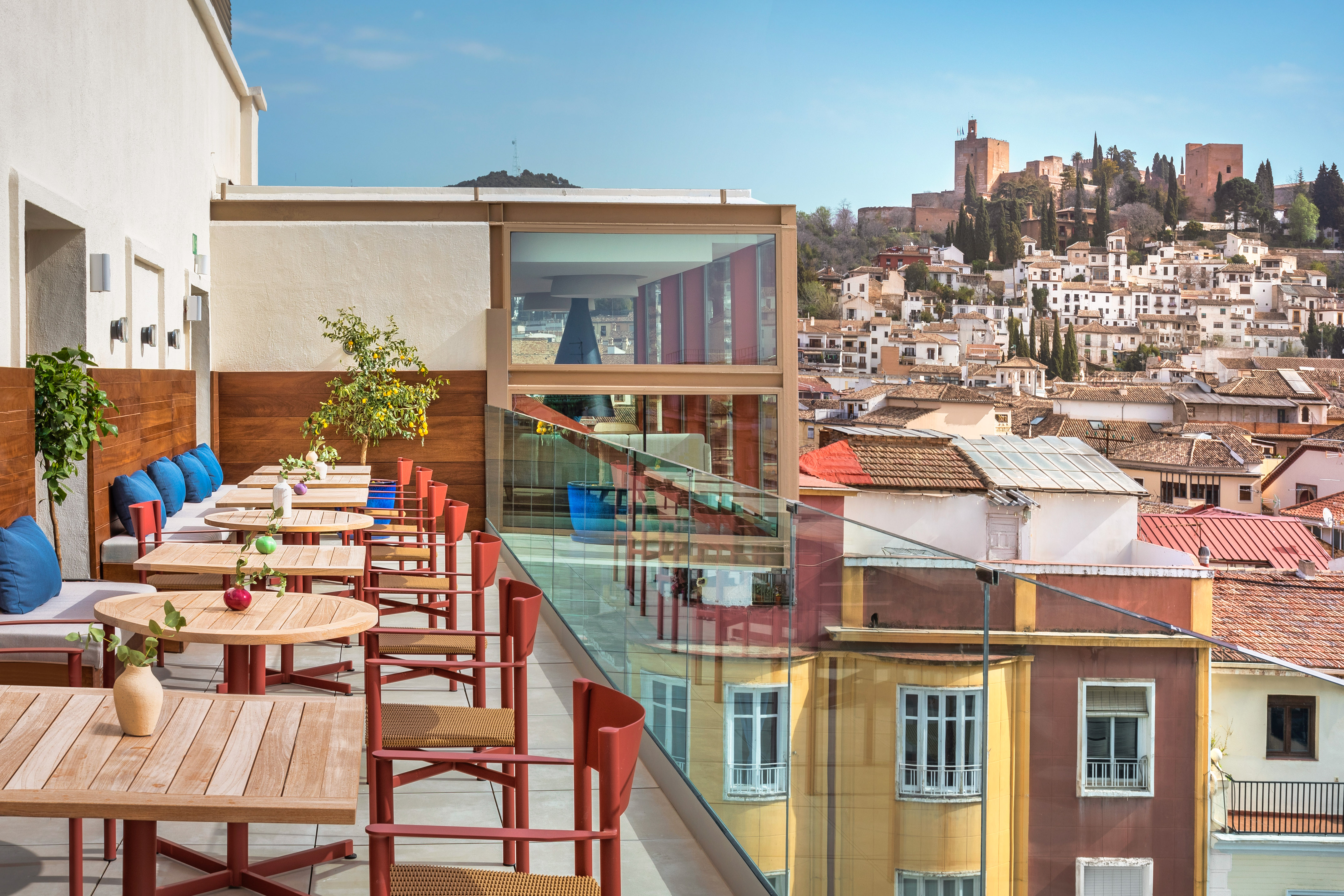 Alhambra view from Granada rooftop terrace with outdoor dining tables.