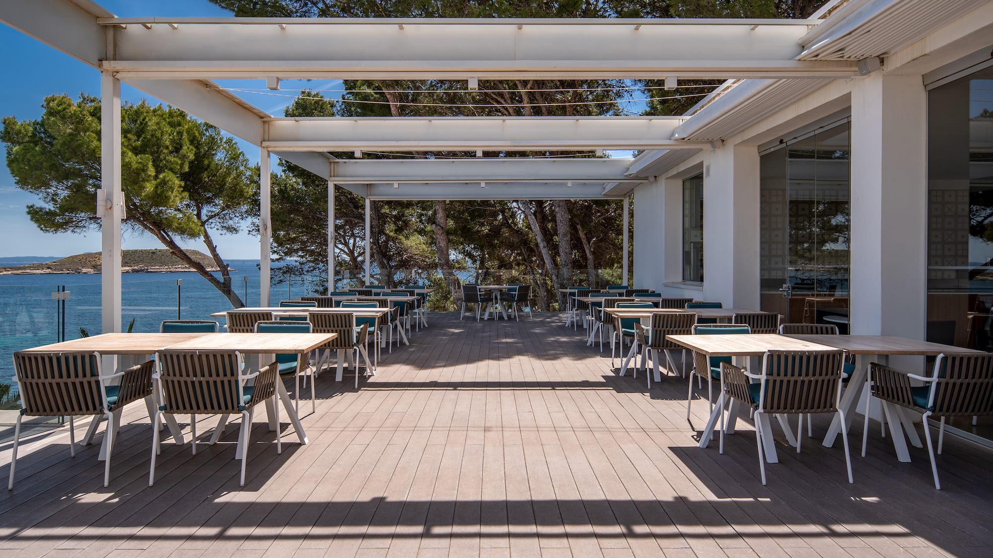 a white building with tables and chairs on a deck