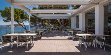 a white building with tables and chairs on a deck