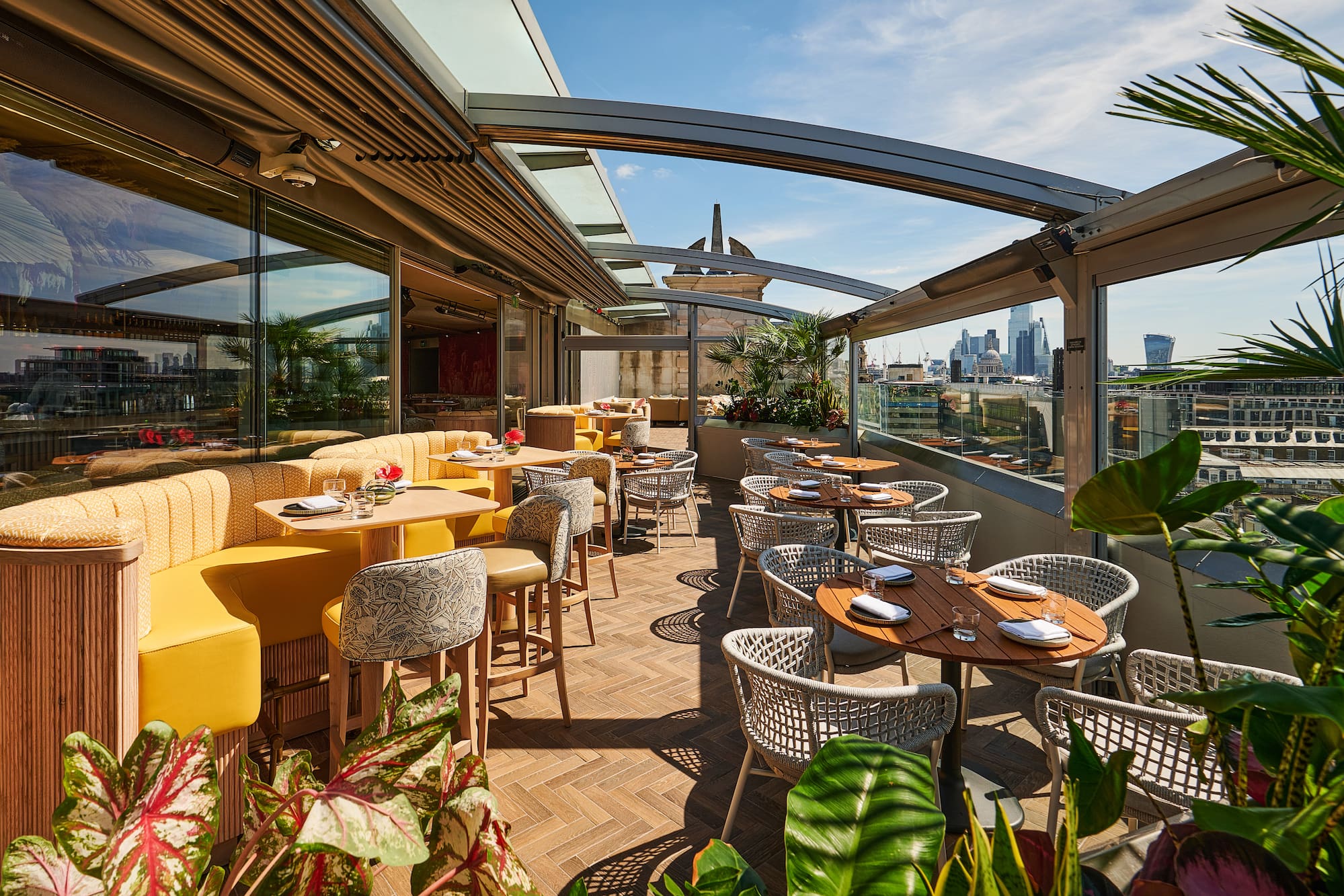 Elegant rooftop terrace with modern seating, London skyline, and lush greenery.