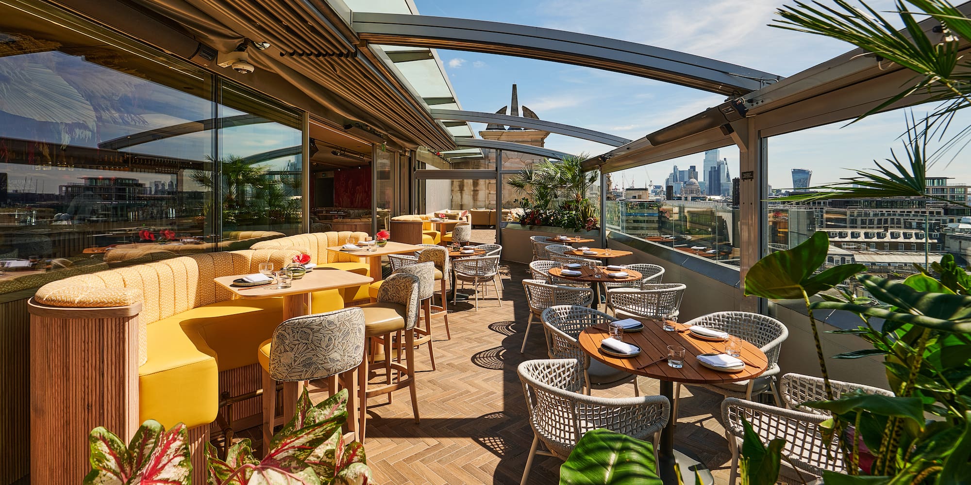 Elegant rooftop terrace with modern seating, London skyline, and lush greenery.
