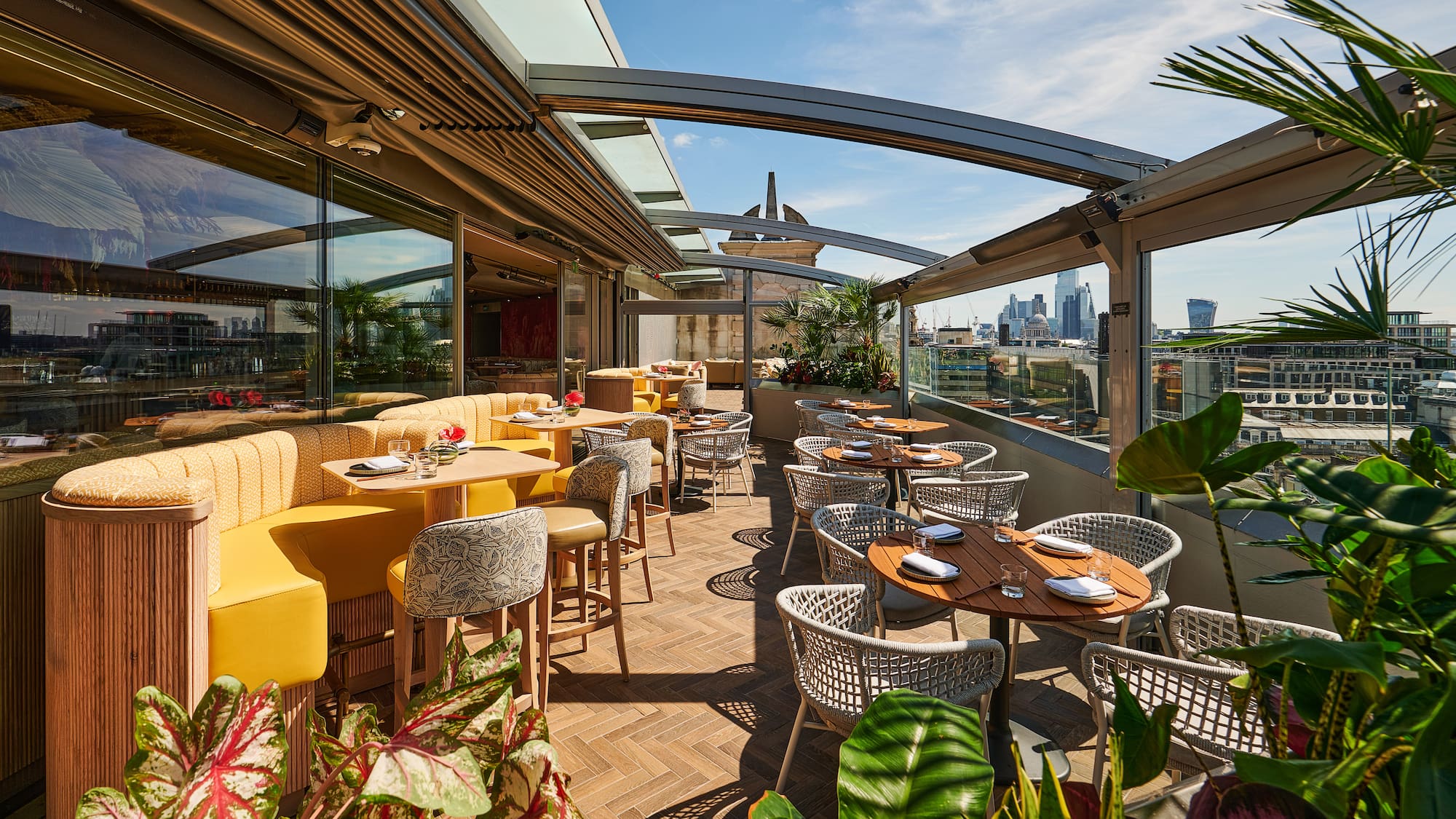 Rooftop terrace restaurant with London skyline view and sunny outdoor seating.