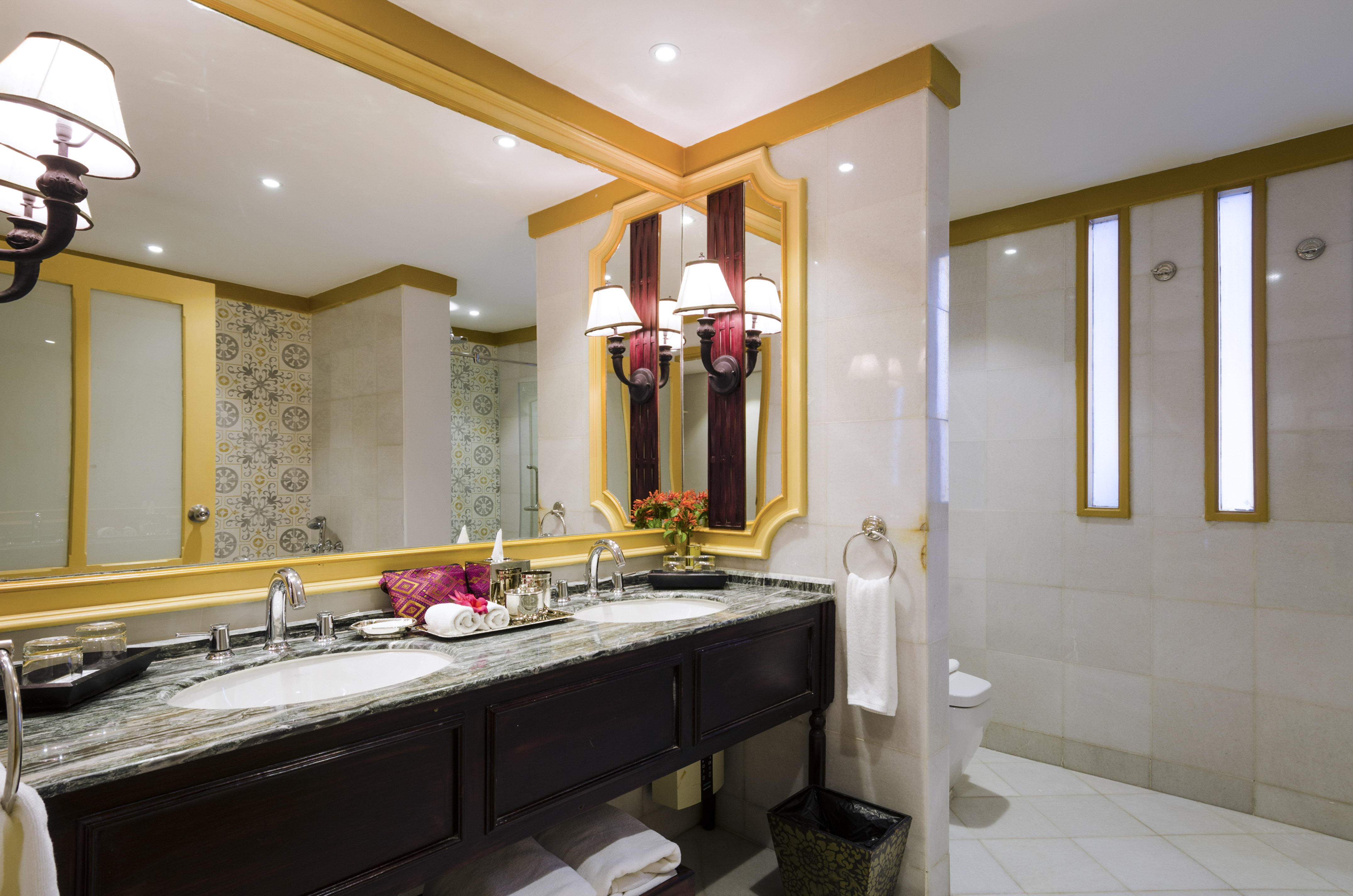 Elegant hotel bathroom with double vanity, marble counter, and gold mirrors.