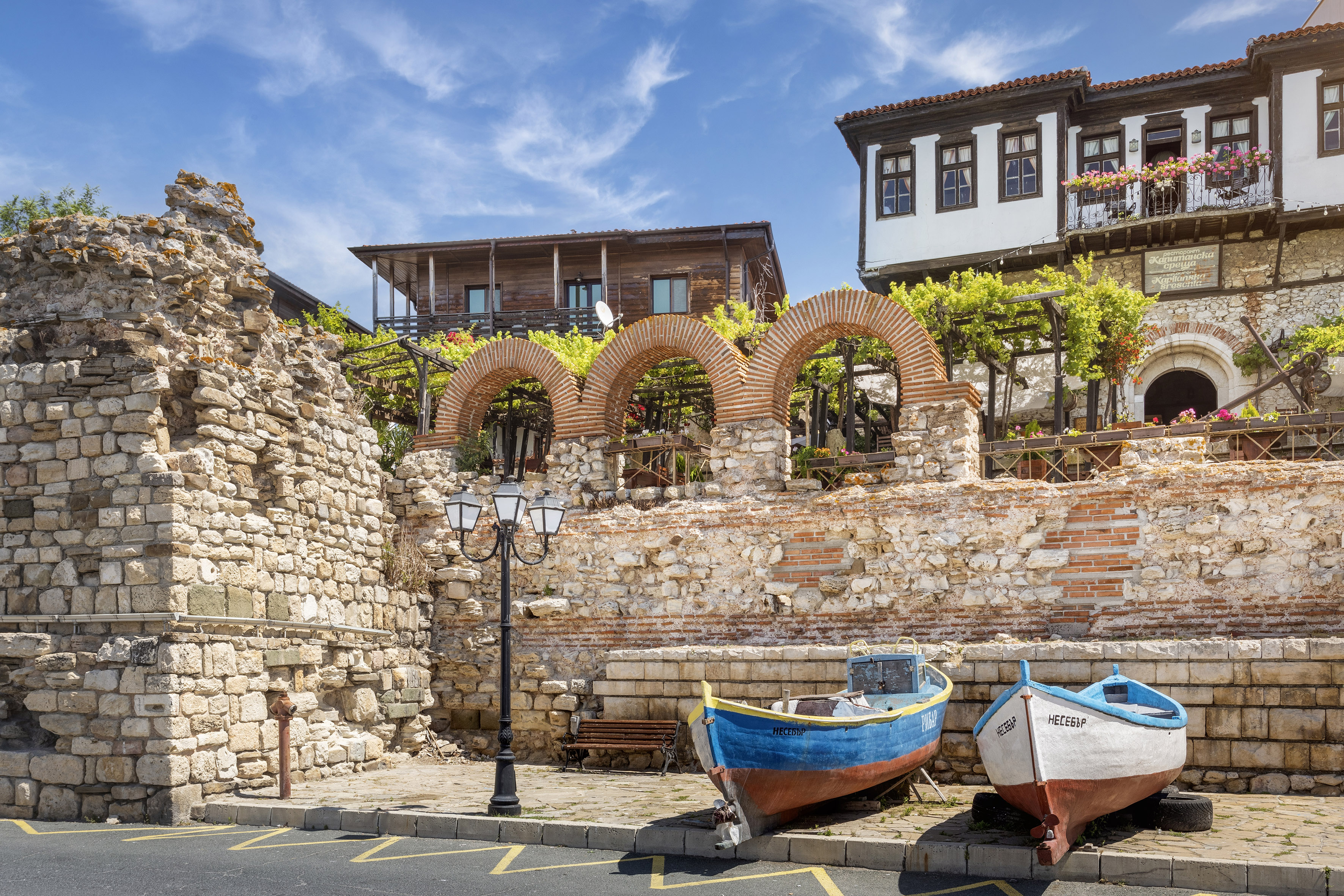 boats parked on the side of a road next to a stone wall
