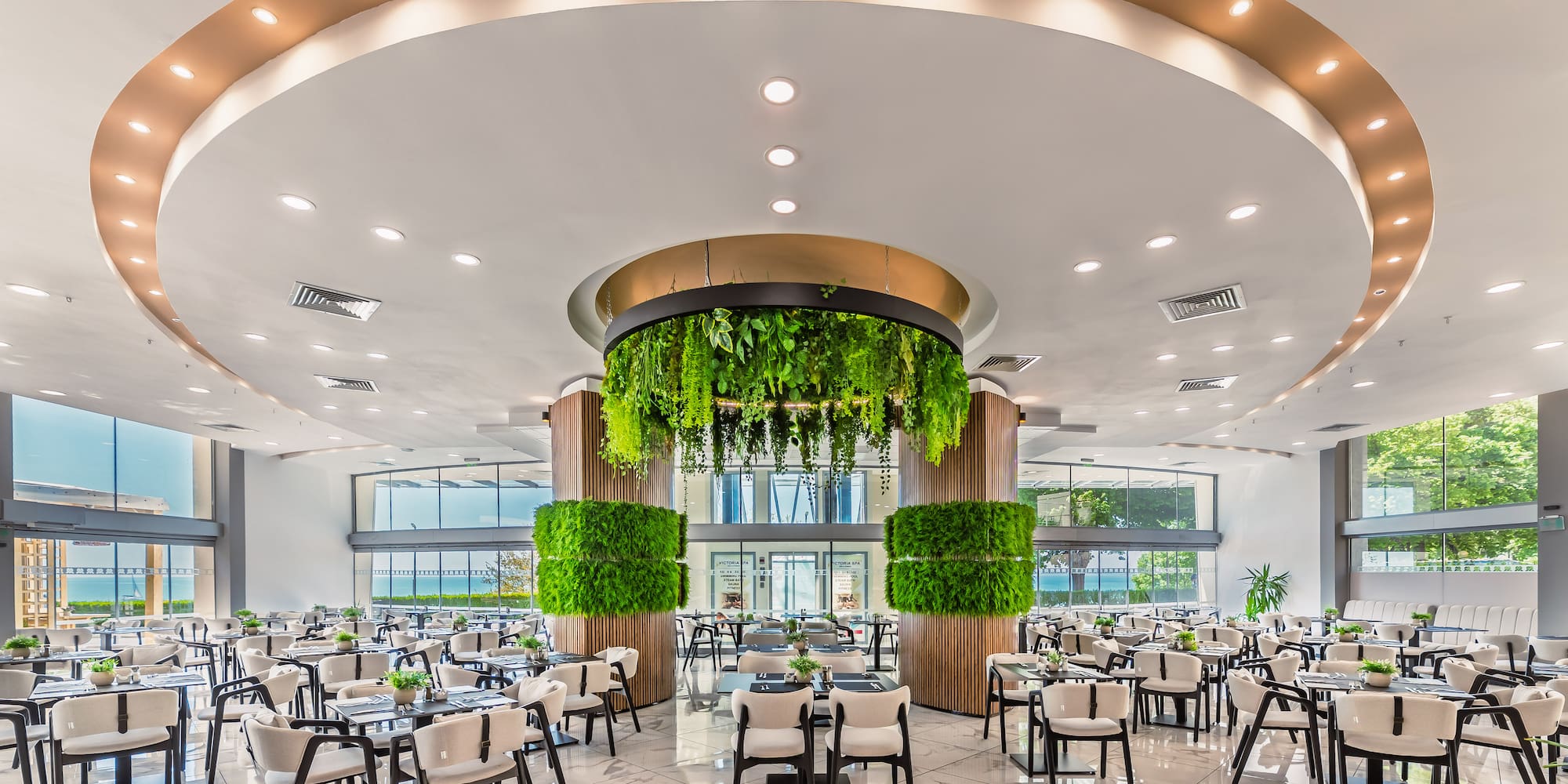 Modern elegant restaurant dining area with lush green plant decorations.