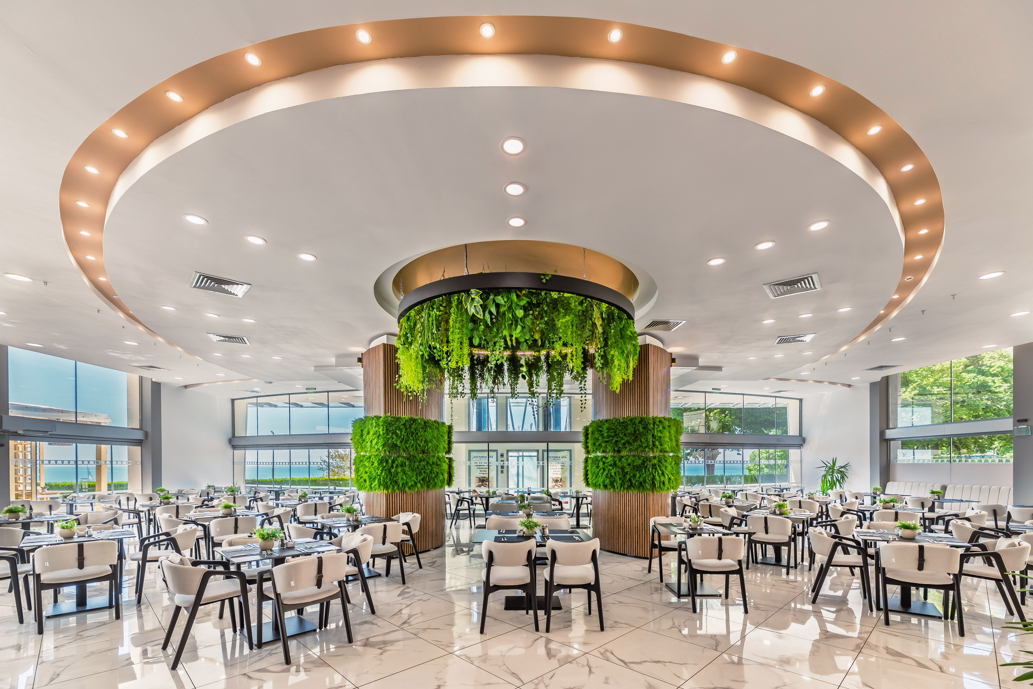 Modern elegant restaurant dining area with lush green plant decorations.