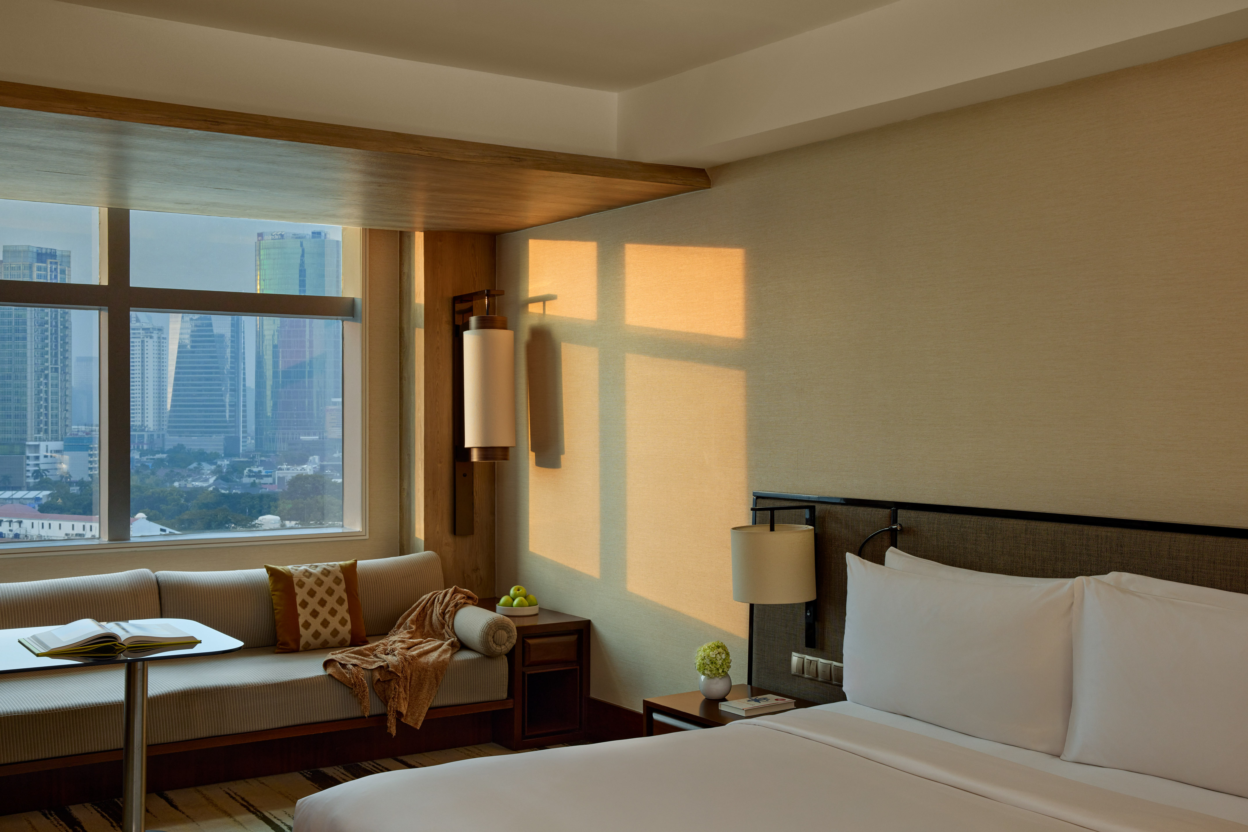 Luxury hotel room with city view, comfortable bed, and window lounge.