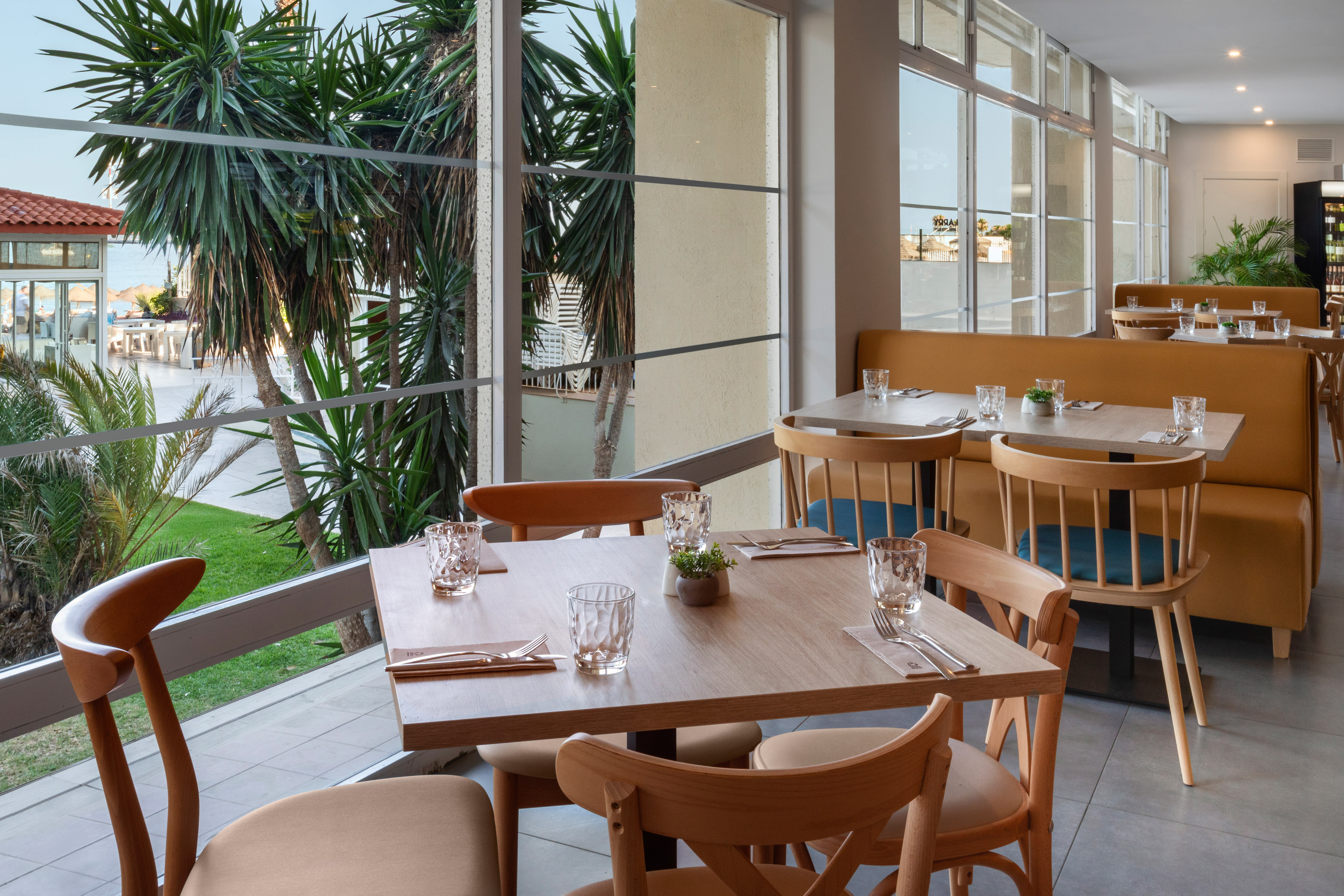 Modern restaurant dining area with tropical view through large windows.