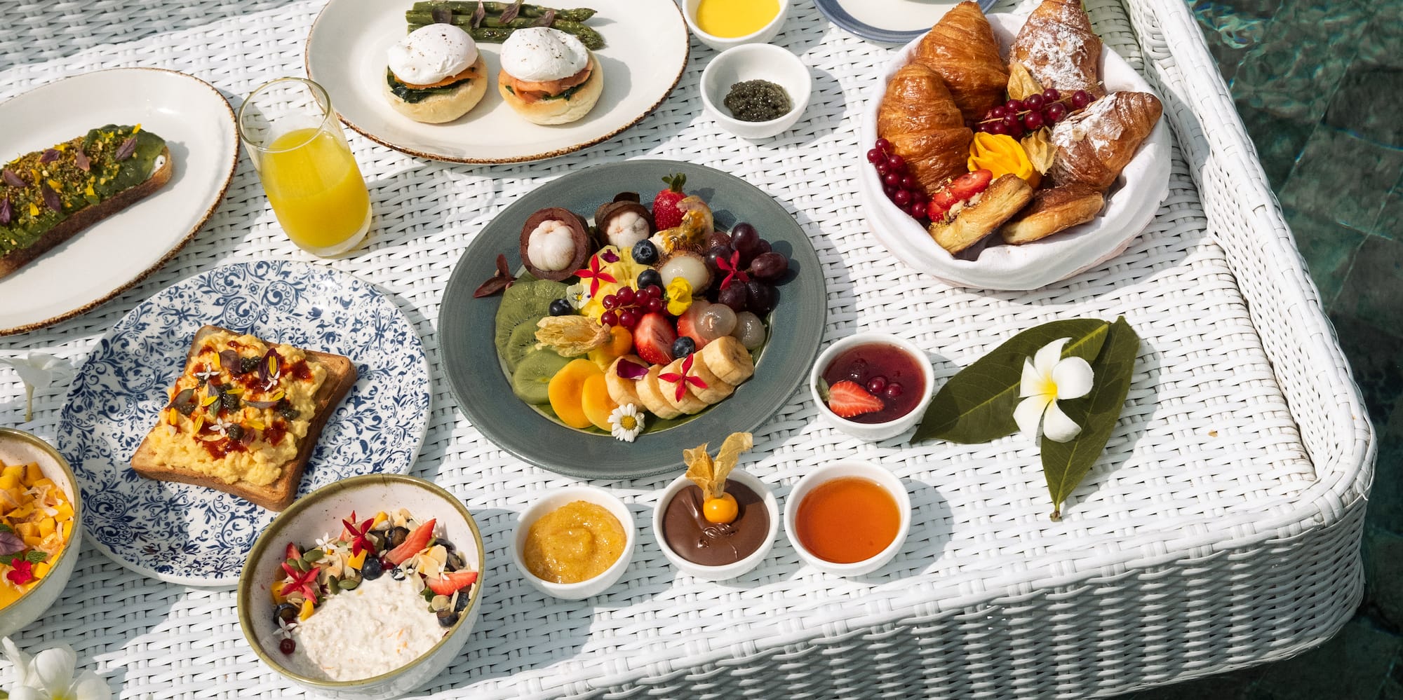 Luxury floating breakfast in pool with fruit, pastries, coffee, and eggs.
